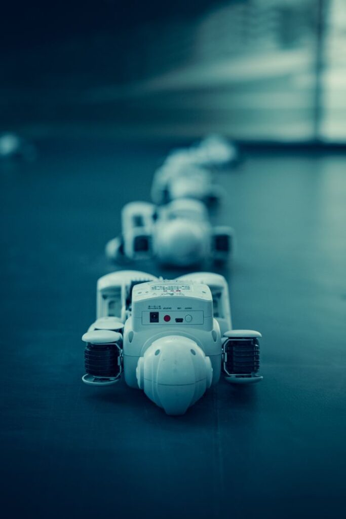 Vertical shot of white robots aligned on a dark surface, emphasizing technology.